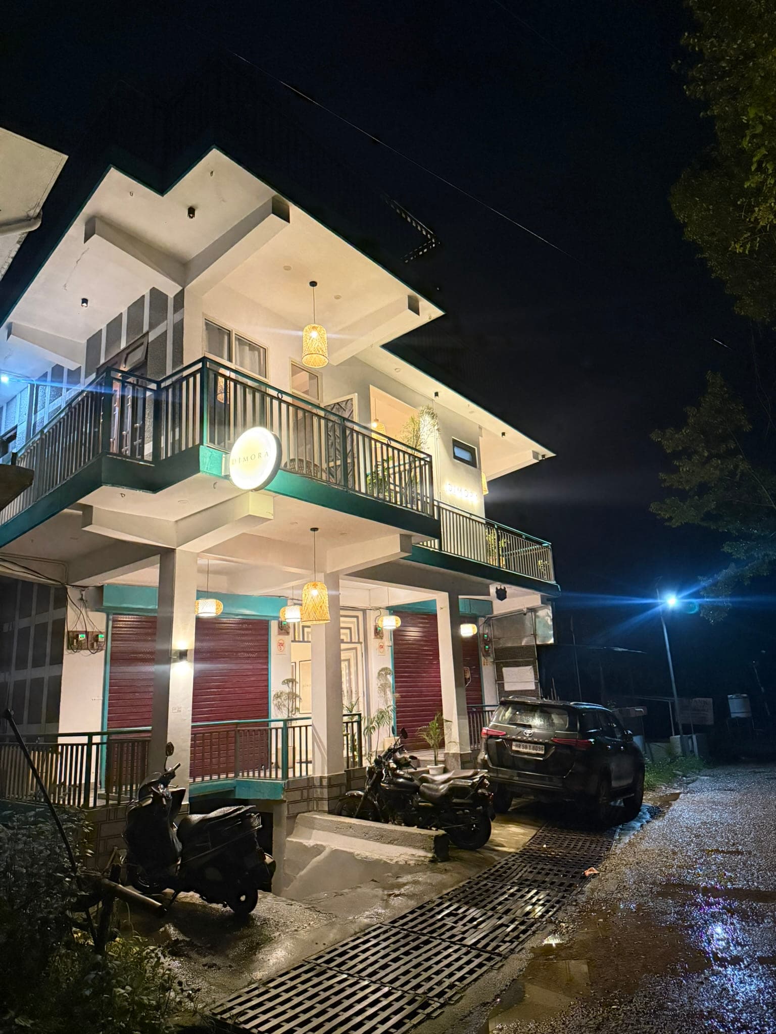 The Dimora Homes building lit at night in Chougan, Bir, with balconies and glowing lanterns