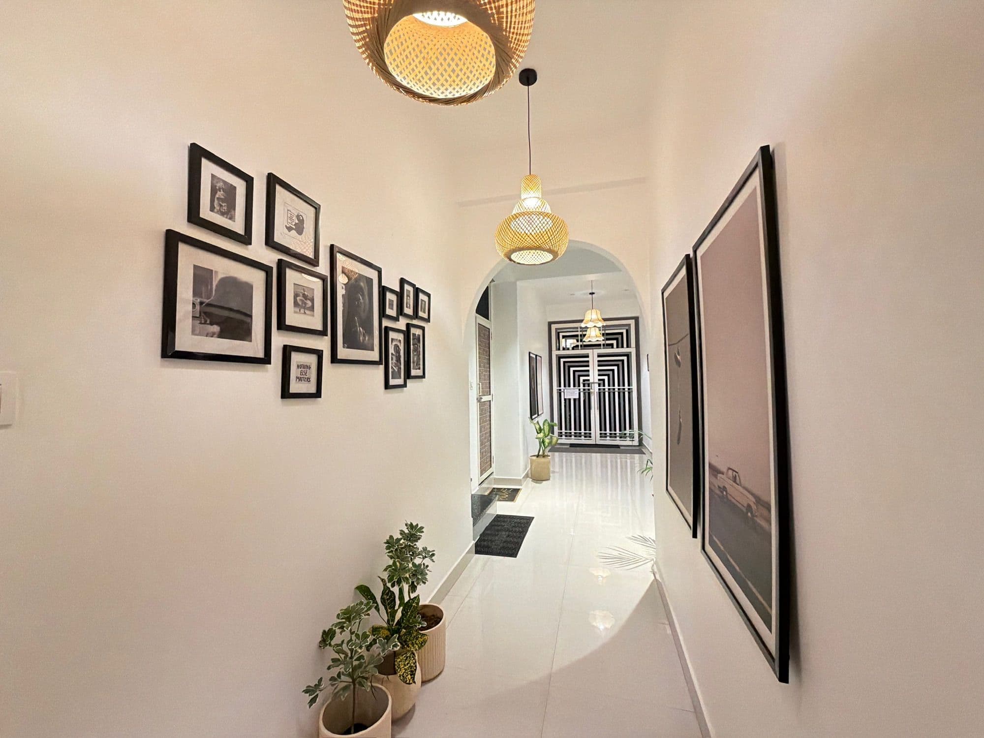 Arched passage between corridors at Dimora Homes, with plants and a woven pendant lamp