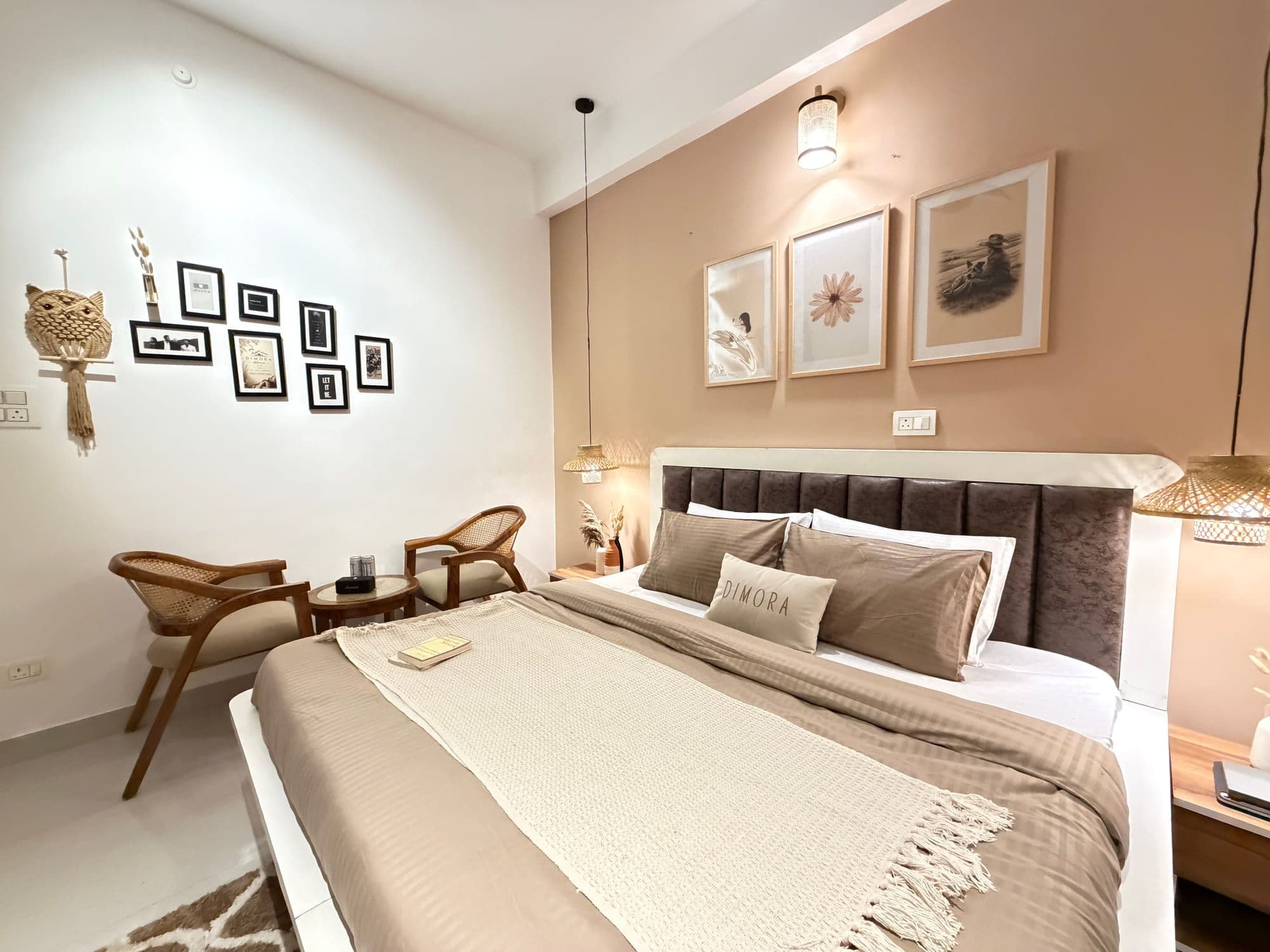 Deluxe King room at Dimora Homes with a king bed against a mocha accent wall, framed prints and pendant lamps
