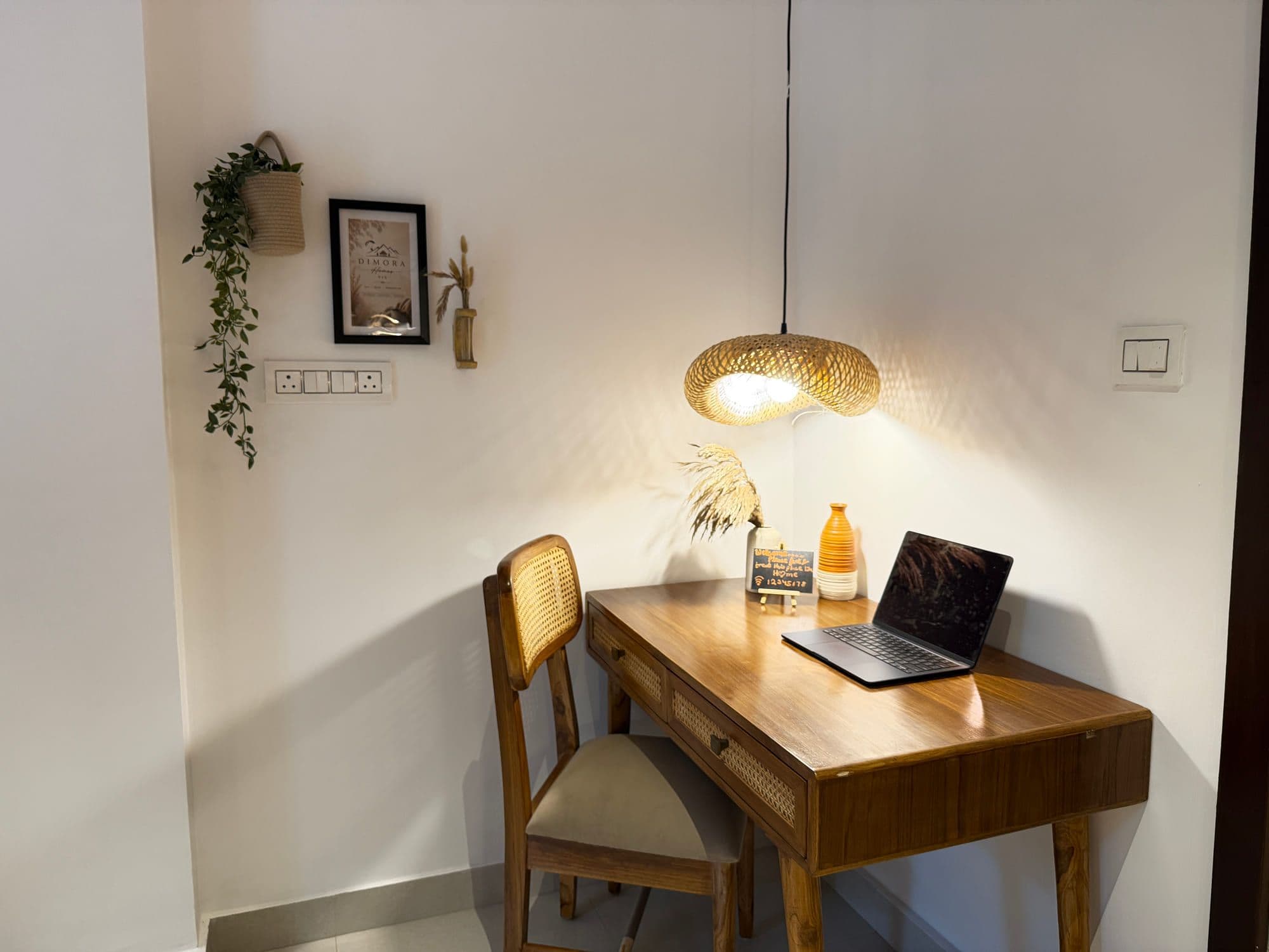 Wooden desk with a laptop, cane chair and framed print — a room set up to work from