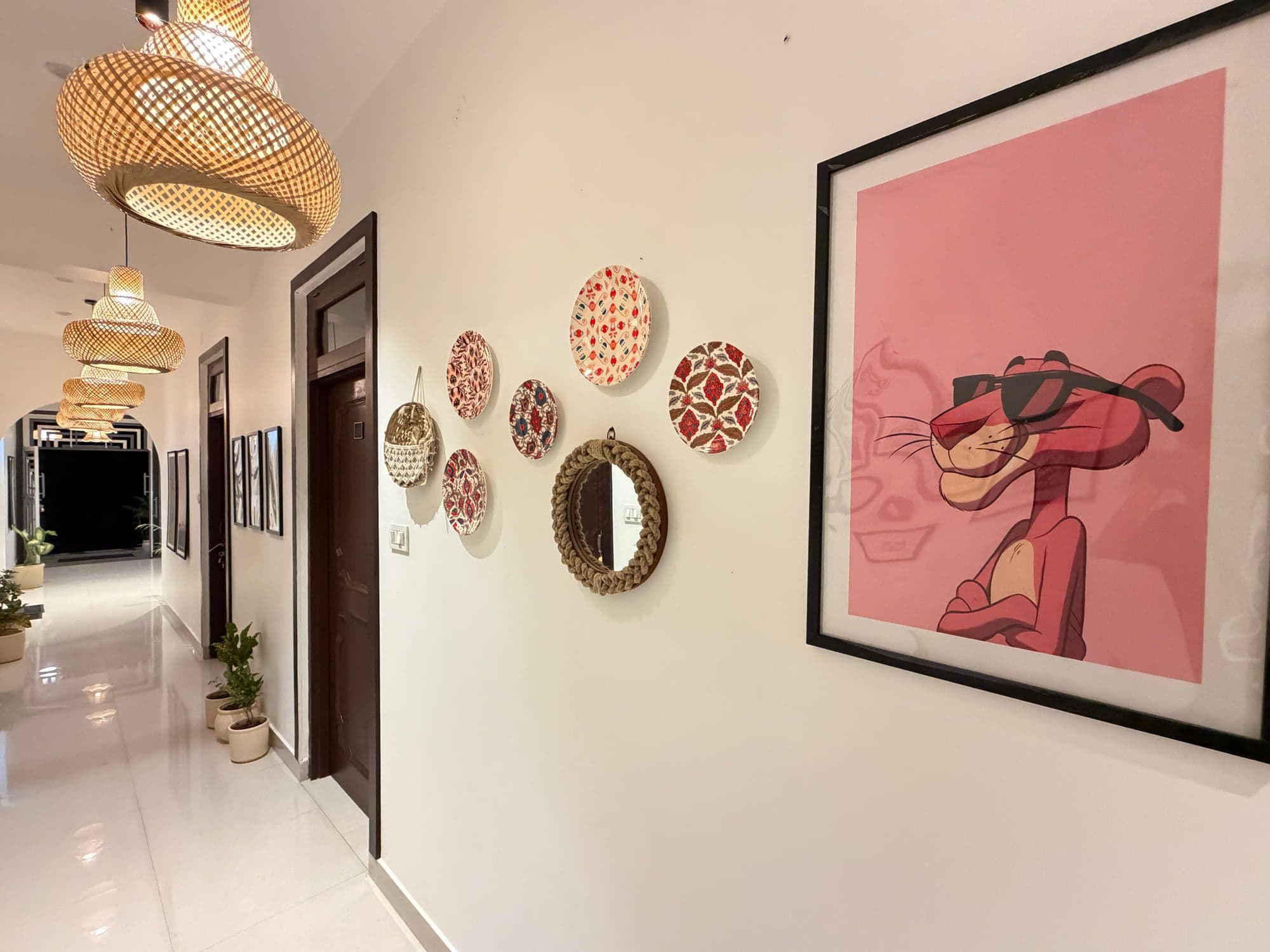 Hand-painted ceramic plates, mirrors and a pink framed print arranged along a corridor wall