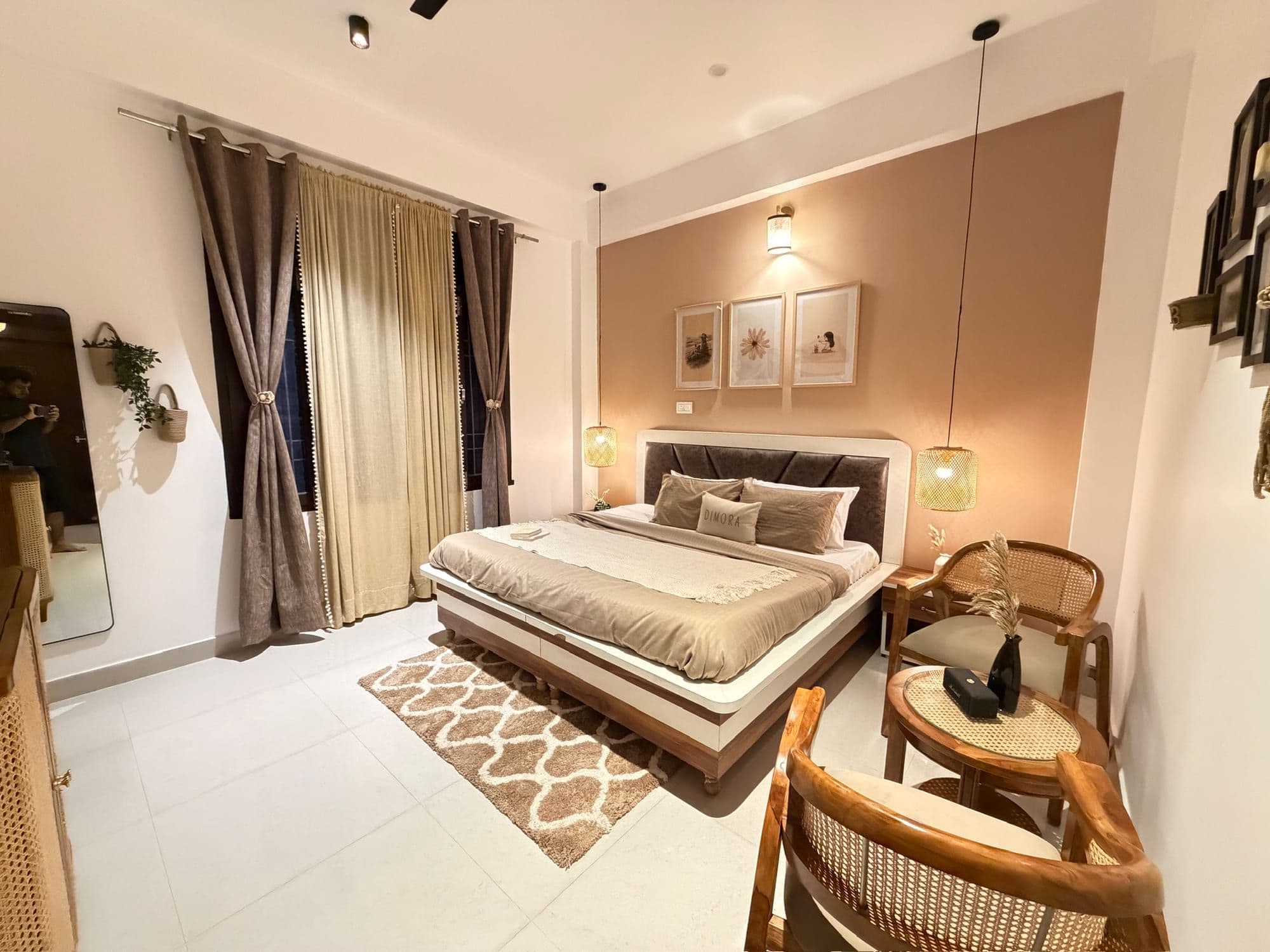 Deluxe King room at Dimora Homes with a mocha accent wall, king bed, cane armchairs and pendant lamps